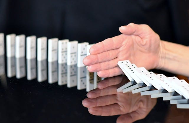Bild: Hand stoppt Domino-Reihe