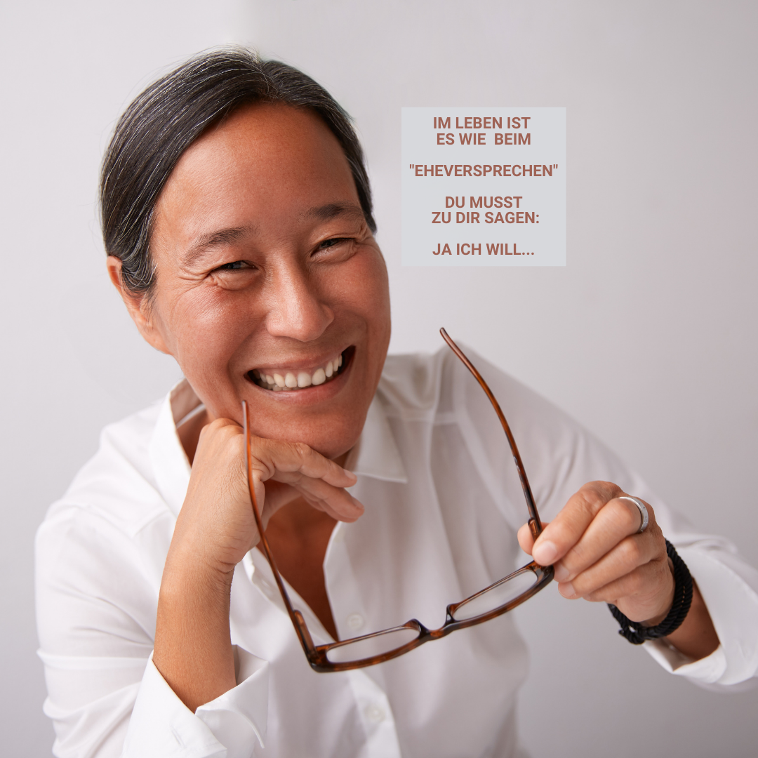 Frau lacht mit Brille in der Hand