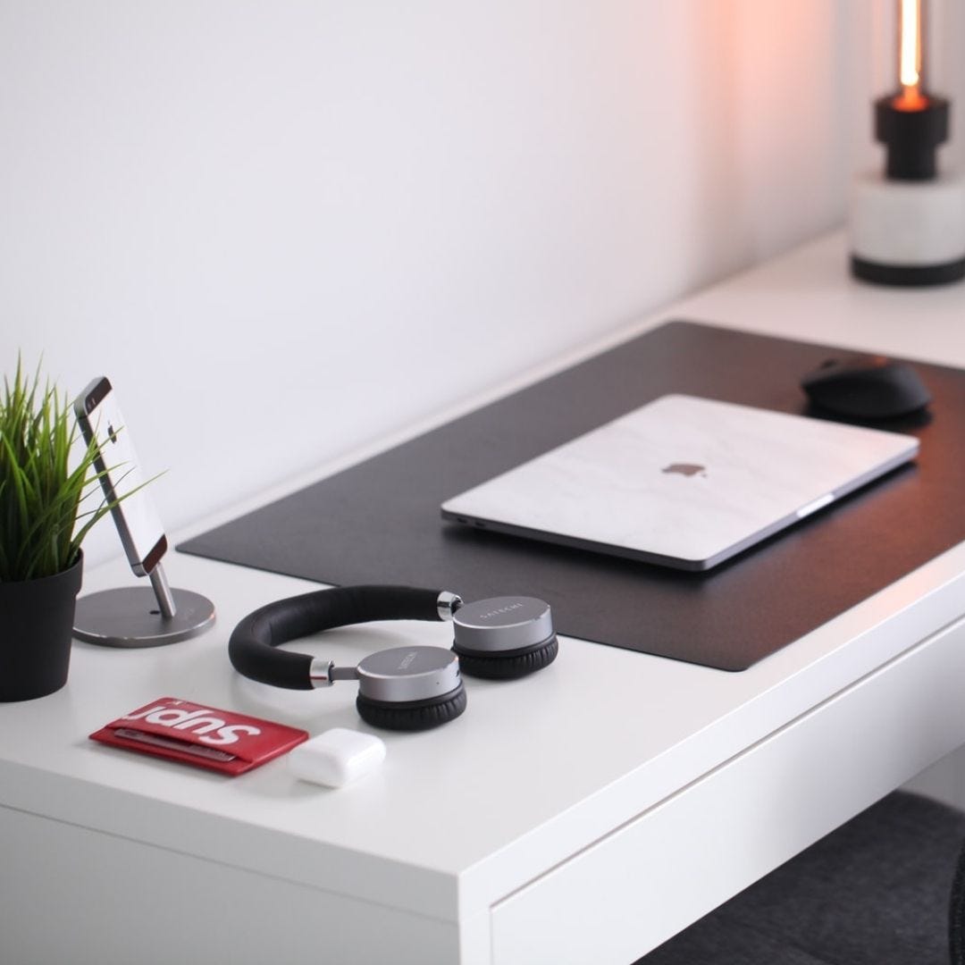 Angular shot of desk with MacBook and headphones atop it