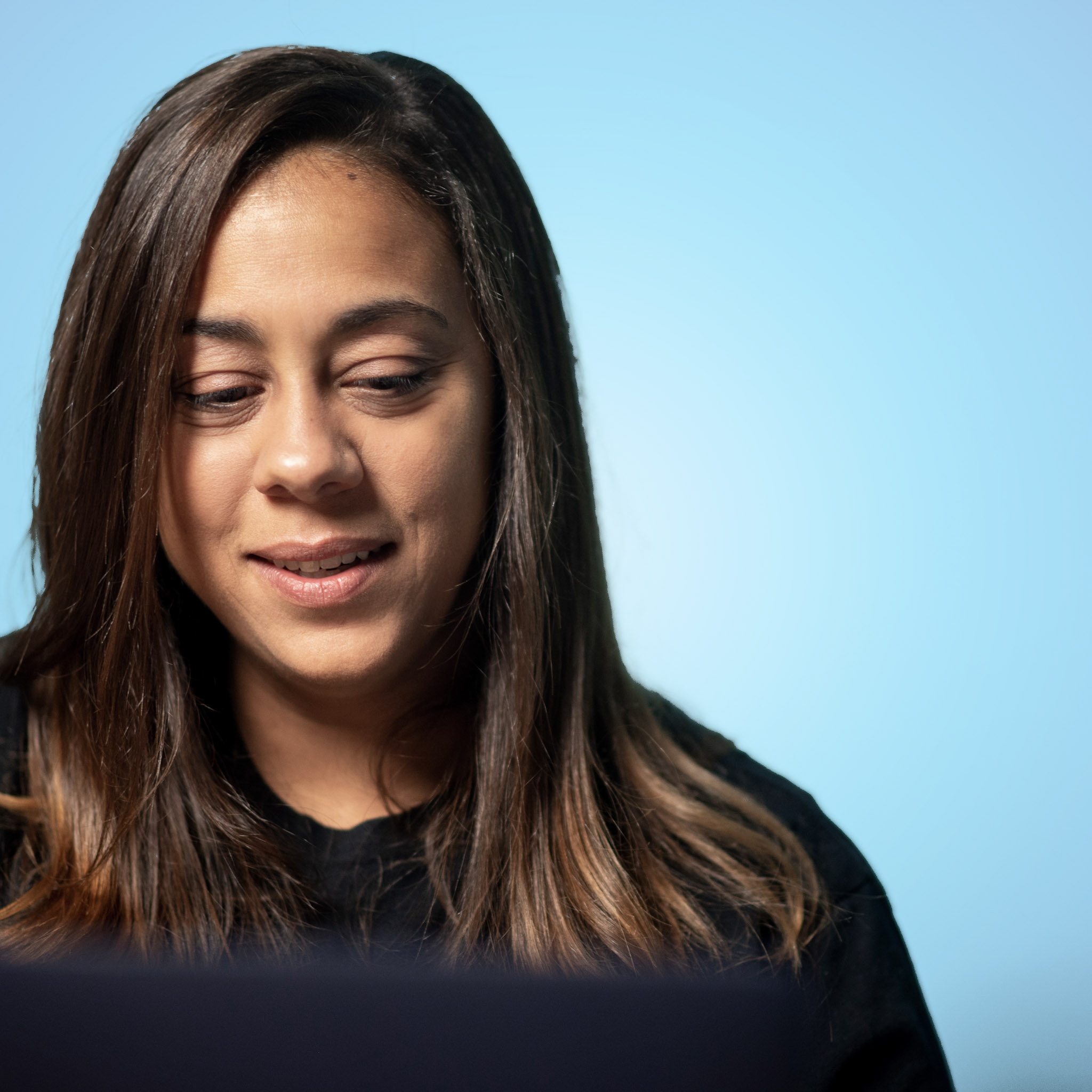Coffee & Cash host Darcy Erickson looking down at a computer screen, a light blue background behind her