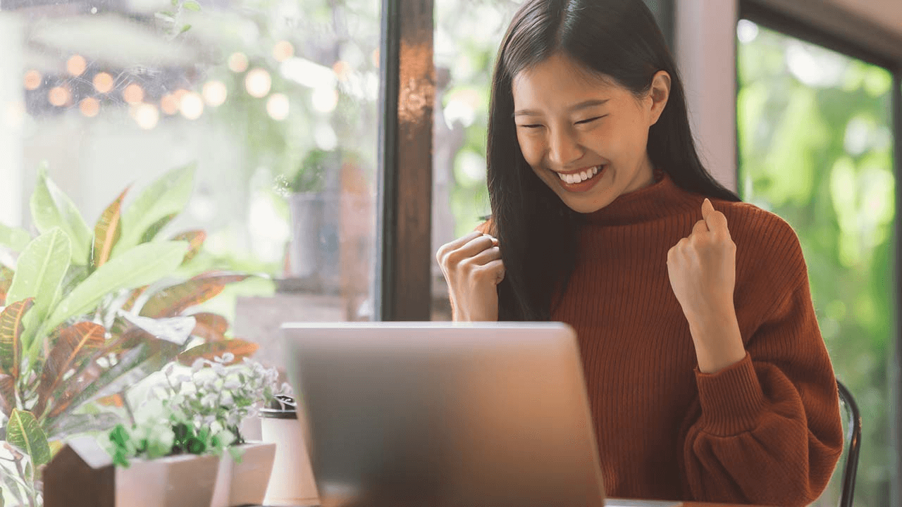 Young woman is looking at her laptop screen and laughing 