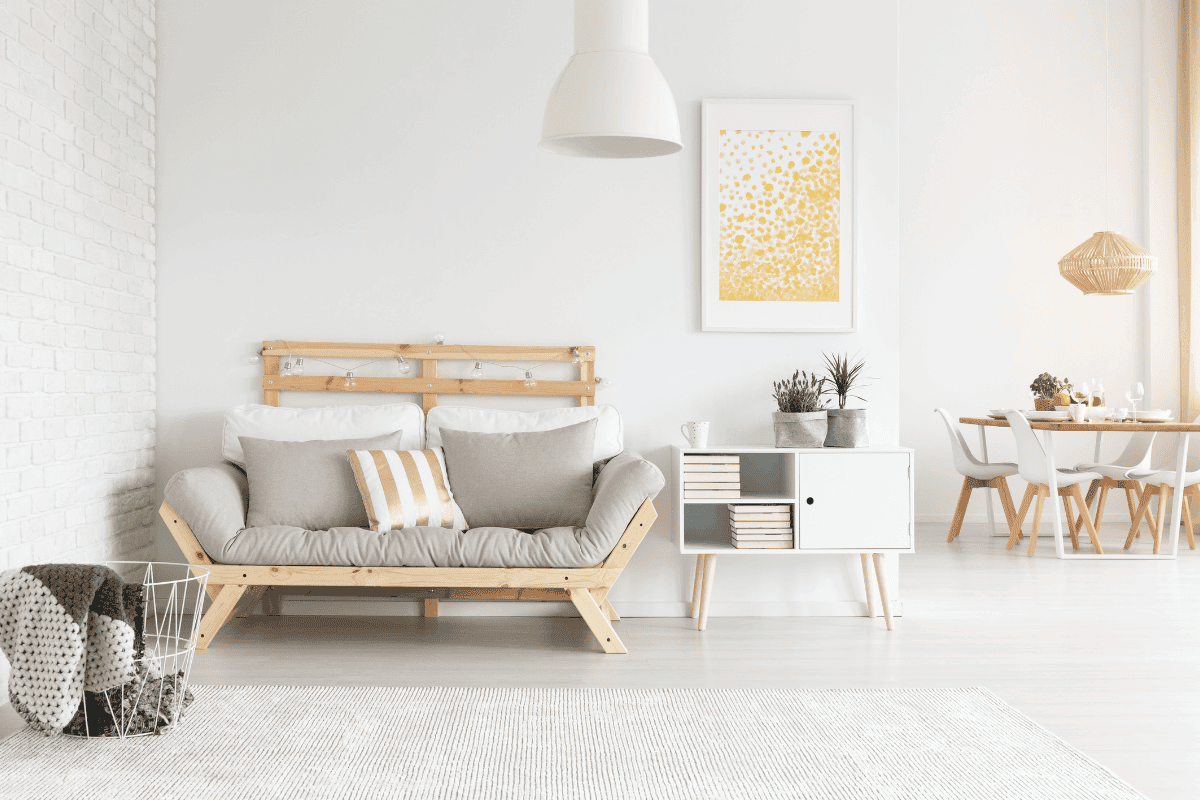 Ein beiges Sofa steht in einem hell und modern eingerichteten Wohnzimmer, mit einer Essecke im Hintergrund.