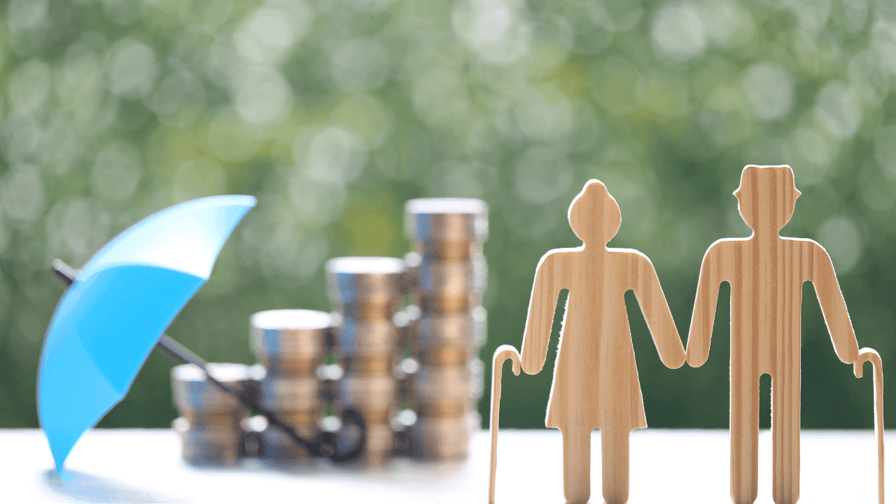 Hände schützend über Modellen eines Autos, eines Hauses und einer Familie aus Papier, symbolisieren umfassende Versicherungslösungen für Vermögens- und Familienschutz.