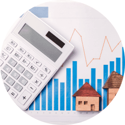 Ein Taschenrechner liegt auf einem Papier mit blauen Balkendiagrammen, über denen eine rote Aufwärtstrendlinie verläuft, neben zwei stilisierten Holzhäusern, symbolisierend die sorgfältige Planung und Berechnung im Rahmen einer Beratung zur Immobilienfinanzierung.