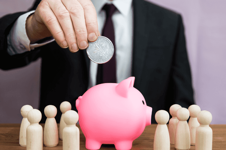 Das Konzept der betrieblichen Altersvorsorge (bAV): Der Arbeitgeber legt eine Münze in ein rosa Sparschwein, was die finanzielle Unterstützung der Mitarbeiter*innen bei deren Altersvorsorge symbolisiert.