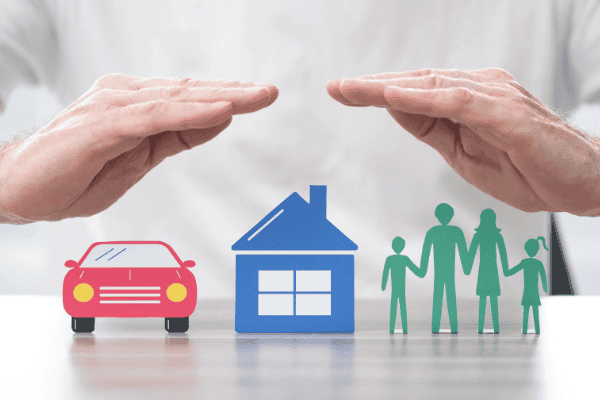 Schutz für Familie, Haus und Auto: Hände schützen symbolisch Modelle einer Familie, eines Hauses und eines Autos, um die Bedeutung leistungsstarker Versicherungen zu veranschaulichen, was einen Versicherungsvergleich empfehlenswert macht.