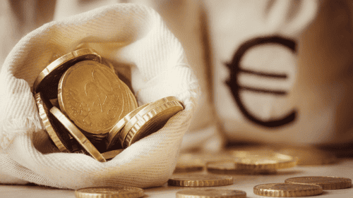 Ein offener Geldbeutel voller Euromünzen auf einem Tisch, symbolisiert effektives Sparen und Kapitalbildung für finanzielle Sicherheit und Notfallrücklagen.