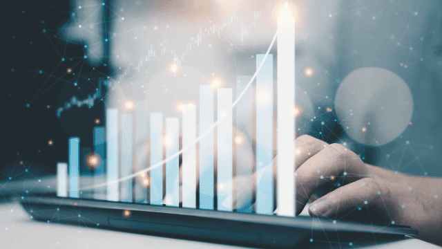 Eine Hand tippt auf einem Tablet, das helle, aufsteigende Finanzdiagramme auf dem Bildschirm anzeigt, symbolisch für strategische Investitionen und Geldanlagen. Dieses Bild vermittelt die Wichtigkeit von fortschrittlicher Technologie und datengesteuerter Analyse bei der Finanzplanung, speziell zugeschnitten auf Frauen, die ihre Finanzen und Investitionen eigenständig verwalten möchten, um finanzielle Unabhängigkeit zu erreichen.