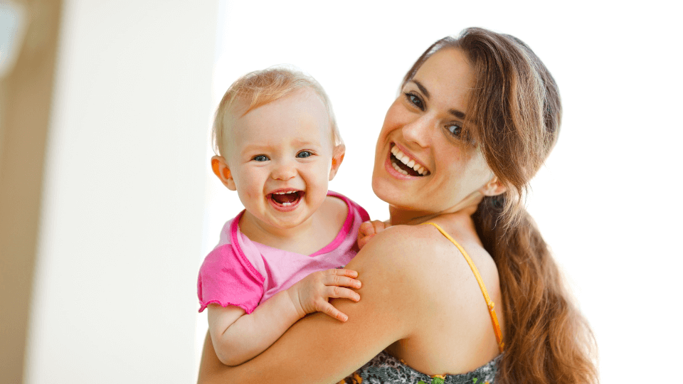 Junge Mutter mit Baby auf dem Arm – glückliche Frau mit Kind, die finanzielle Unabhängigkeit und Familienleben in Einklang bringen möchte.