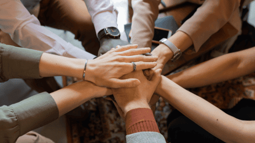 Teamwork in der betrieblichen Krankenversicherung – diverse Hände symbolisieren Zusammenhalt und gemeinsame Gesundheitsvorsorge im Unternehmen.