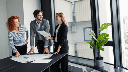 Individuelle Finanzberatung für Berufstätige – junge Fach- und Führungskräfte im Gespräch über Geldanlage, Altersvorsorge und Immobilieninvestments in modernem Büroambiente.