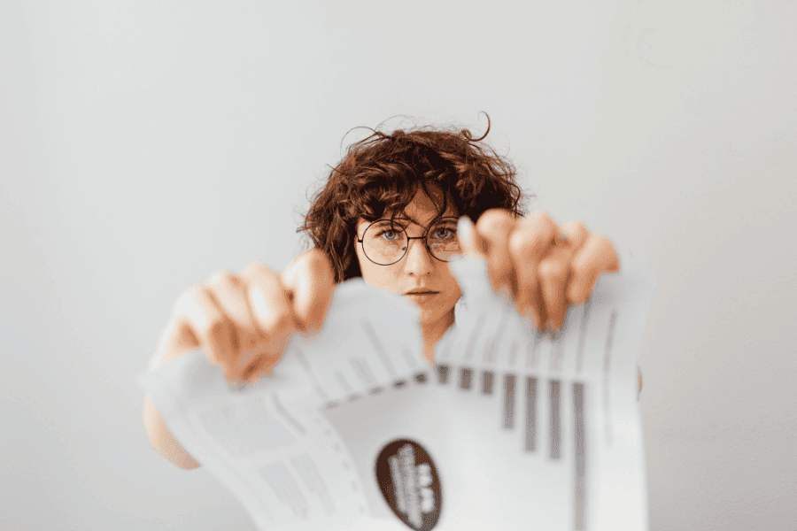 Person zerreißt Verträge – vorschnelle Kündigung von Altersvorsorge, ETF-Sparplan oder Versicherungen und Verlust langfristiger Rendite