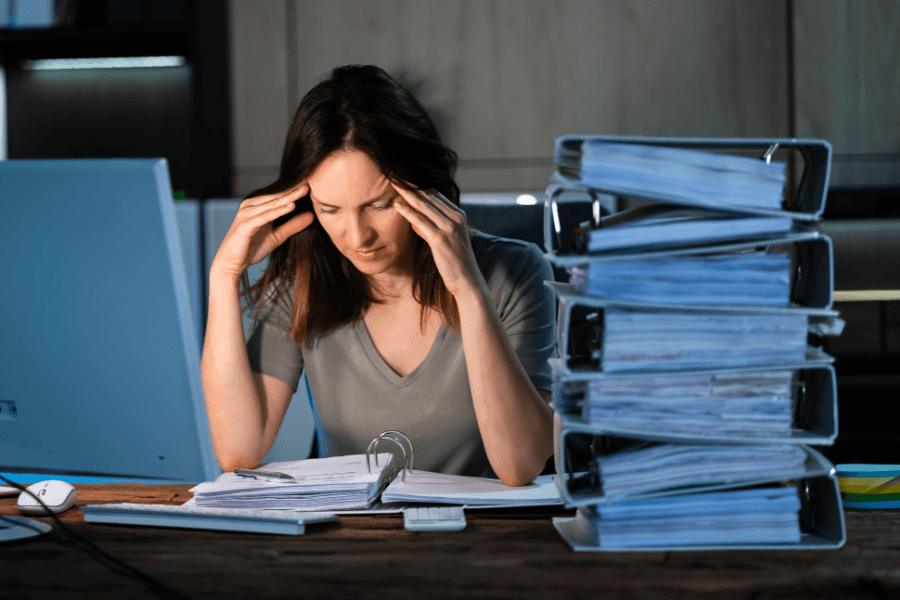 Selbstständige Person mit Unterlagen und Aktenordnern am Schreibtisch – Symbol für die Herausforderungen der Finanzorganisation und die Bedeutung einer vorausschauenden Finanzplanung für Selbstständige