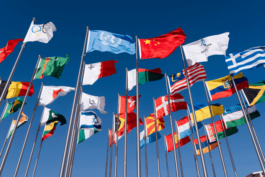 Internationale Flaggen vor blauem Himmel als Sinnbild für weltweite Geldanlage, globale Aktienmärkte, Schwellenländer, Industrieländer und eine breit diversifizierte Anlagestrategie.